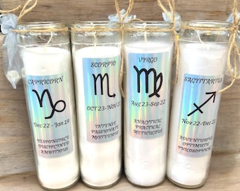 May include: Four glass candle jars with labels featuring the zodiac signs Capricorn, Scorpio, Virgo, and Sagittarius. Each label includes the sign's symbol, dates, and personality traits.
