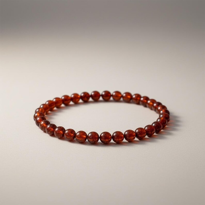 May include: A beaded bracelet featuring small, round, reddish-brown beads. The bracelet is circular and appears to be made of a natural material. The beads are evenly spaced and have a slightly translucent appearance.