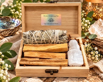 May include: A light-coloured wooden box containing a home cleansing kit. Inside is a sage bundle tied with white string, three rectangular palo santo wood sticks, and a white selenite crystal. A label reads Home Cleansing Kit Sage, Palo Santo & Selenite.
