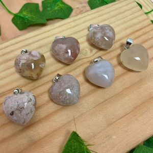 Puede incluir: Siete colgantes de &aacute;gata en forma de coraz&oacute;n con un aro de plata. Los colgantes son de varios tonos de blanco, gris y rosa con patrones de &aacute;gata marr&oacute;n y blanco.