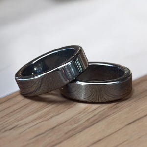 May include: Two silver rings with a textured, brushed finish. The rings are stacked on top of each other.