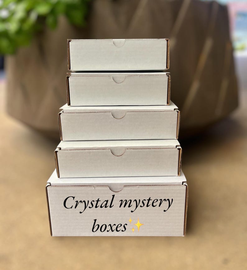 May include: A stack of five white boxes with the words "Crystal mystery boxes" printed on the bottom box.