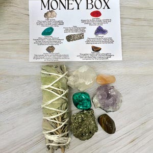 Peut inclure: Un kit de bo&icirc;te &agrave; argent avec divers cristaux, dont du quartz clair, de la malachite, de la pyrite, de la cornaline, de l'am&eacute;thyste, de l'&oelig;il de tigre et de la sauge. Le kit comprend &eacute;galement un b&acirc;tonnet de sauge blanche.
