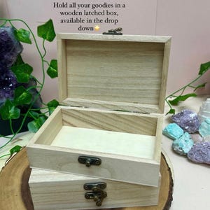 Peut inclure: Une bo&icirc;te en bois avec un loquet et un couvercle &agrave; charni&egrave;res. La bo&icirc;te est en bois clair et a une finition naturelle. La bo&icirc;te est pos&eacute;e sur une surface en bois.