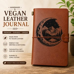 May include: Brown vegan leather journal with a mountain and moon design. The journal has a strap closure and the words "VEGAN LEATHER JOURNAL" are printed on the cover. The journal is handmade and durable.