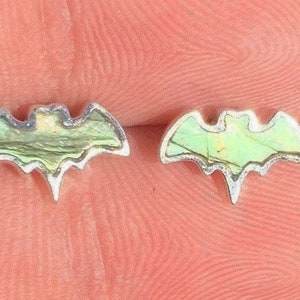 May include: A pair of silver bat earrings with iridescent green abalone shell inlays.