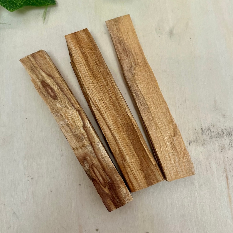 May include: Three brown palo santo sticks, a type of fragrant wood used for smudging and cleansing rituals.