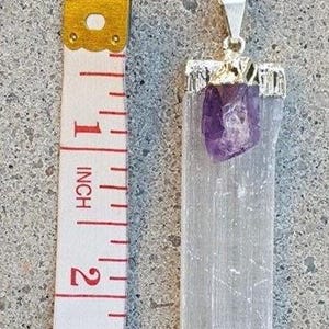 May include: A silver chain necklace with a white selenite crystal pendant and a small amethyst crystal. The pendant is approximately 1 inch in length.