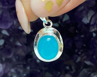 May include: A silver pendant featuring a light blue oval gemstone. The pendant is on a silver chain.