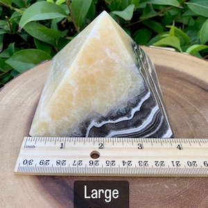 May include: A pyramid-shaped decorative object with a yellow and black banded pattern. The base measures approximately 10 cm. The text "Large 100mm" is visible on the image.