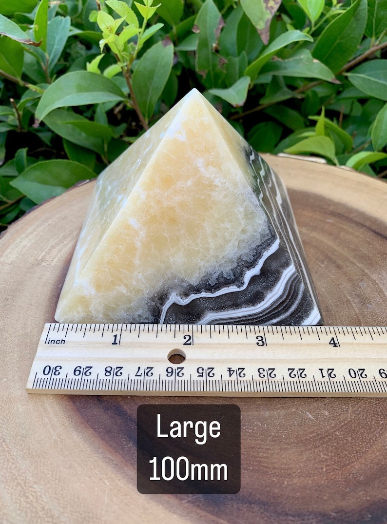 May include: A pyramid-shaped decorative object with a yellow and black banded pattern. The base measures approximately 10 cm. The text "Large 100mm" is visible on the image.