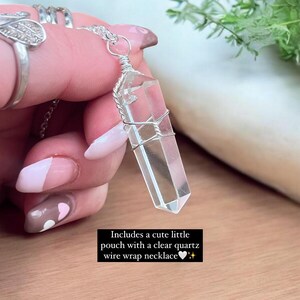 Puede incluir: Un colgante de cristal de cuarzo transparente envuelto en alambre plateado en una cadena de plata. El collar lo sostiene una mano con un dise&ntilde;o de u&ntilde;as en forma de coraz&oacute;n. El texto "Incluye una linda bolsita con un collar de alambre envuelto en cuarzo transparente" est&aacute; debajo de la imagen.