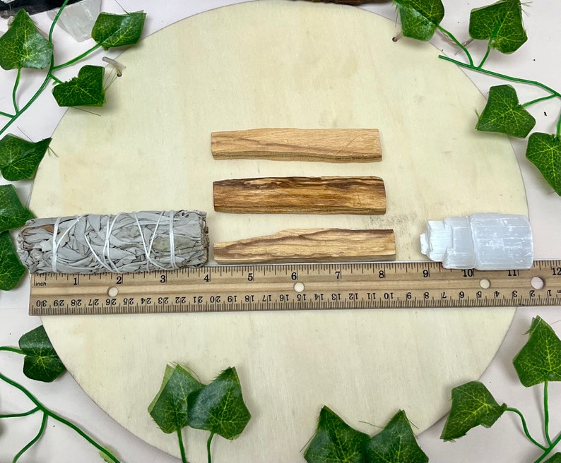 May include: Three brown wooden sticks, a white sage smudge stick, and a white selenite crystal on a wooden surface. The sticks are approximately 4 inches long. The sage stick is approximately 4 inches long. The selenite crystal is approximately 2 inches tall.