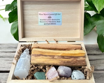 May include: Open wooden box containing crystals and Palo Santo sticks. The box is labeled "New Mom Crystal Gift Set" and includes Amethyst, Green Aventurine, Moonstone, Rose Quartz, and Selenite. The box is open, revealing the contents.