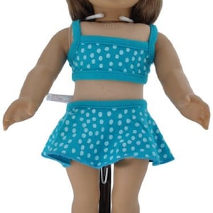 May include: A doll wearing a blue and white polka dot swimsuit with a matching blue and white polka dot hat and white sandals with blue accents.