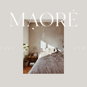 May include: A bedroom interior with a bed made with a light brown linen duvet and pillows. The bed is in front of a concrete wall with a window letting in sunlight. A small plant is in a pot on the floor next to a wooden nightstand with books and a vase with branches. The text "MAORE'" is at the top of the image and "COTTAGE AND CO." is at the bottom.
