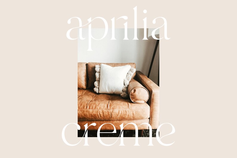 May include: A brown leather sofa with a white pillow with a fringe trim. The sofa is in a living room with a white wall.