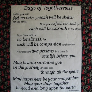 May include: A white fabric with black text that reads "Days of Togetherness" and a poem about love and companionship. The fabric is surrounded by a black and red floral border.