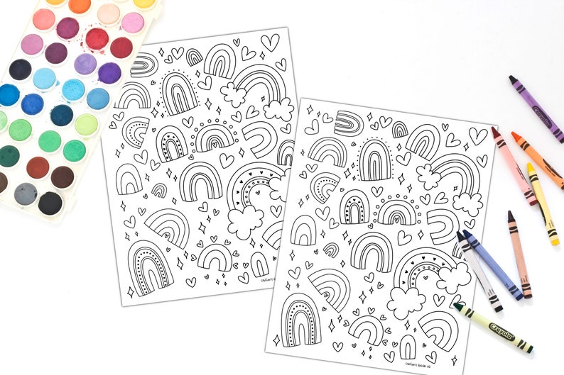 K&ouml;nnte beinhalten: Zwei Schwarzwei&szlig;-Malvorlagen mit einem sich wiederholenden Muster aus Regenb&ouml;gen, Herzen und Sternen. Die Seiten sind von einem Satz Aquarellfarben und Buntstiften umgeben.