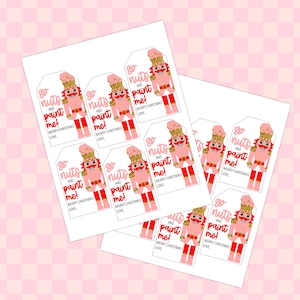 May include: Sheets of gift tags featuring a pink nutcracker design with the text "go nuts and paint me!" and "Merry Christmas! Love." The tags have a white background and red accents. The background is a pink and white checkered pattern.