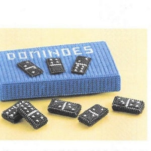 Könnte beinhalten: Eine blaue Canvas-Box mit dem Wort "DOMINOES" auf der Oberseite. Die Box enthält ein Set schwarzer Dominosteine mit weißen Punkten. Es gibt insgesamt sechs Dominosteine, von denen fünf außerhalb der Box liegen.