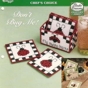 May include: A set of four plastic canvas coasters with a ladybug design. The coasters are black and white checkered with a red ladybug in the center. The coasters are in a box with the text "Fly away home".