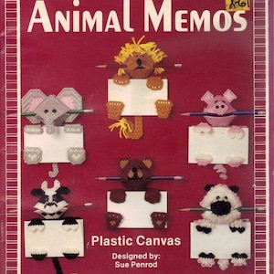 May include: A vintage craft book cover titled "Animal Memos" featuring plastic canvas animal designs. The cover is maroon with white text and includes illustrations of a lion, elephant, pig, bear, cow, and sheep holding blank signs with pencils.