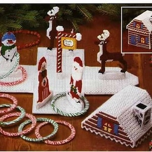 May include: A Christmas-themed craft kit featuring a snowman, reindeer, Santa Claus, and a gingerbread house. The kit includes colorful yarn rings for a ring toss game.