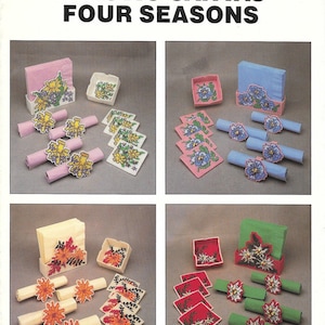 May include: Four plastic canvas needlepoint patterns for napkin holders and coasters. The patterns feature floral designs representing the four seasons: spring with yellow daffodils, summer with blue pansies, fall with orange mums, and winter with white poinsettias.