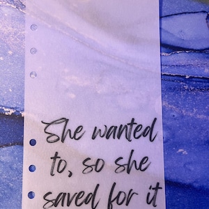 May include: A clear plastic sheet with a quote written in black ink: "She wanted to, so she saved for it."