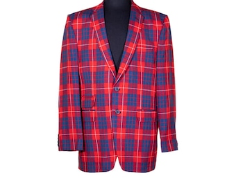 Puede incluir: Una chaqueta de traje de cuadros rojos y azules con dos botones. La chaqueta está en un maniquí negro.