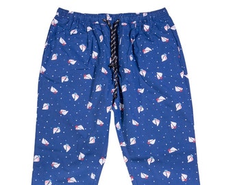 May include: Blue pants with a white sailboat pattern. The pants have an elastic waistband with a drawstring.