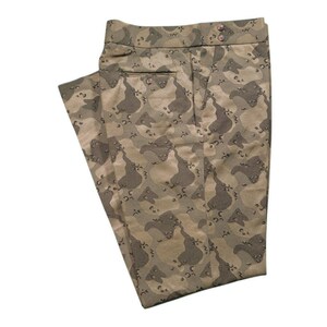 May include: Tan and brown camouflage pants with a button and pocket detail. The pants are made of a patterned fabric and are folded. The pants are a neutral color and could be worn by anyone.