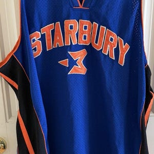 May include: A white ceramic mug with a black handle and the text "But First, Coffee" in a black, handwritten-style font. The mug is on a white surface.