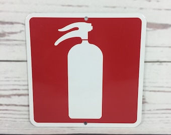 May include: Red square sign with a white fire extinguisher symbol. The sign is made of metal and has rounded corners.