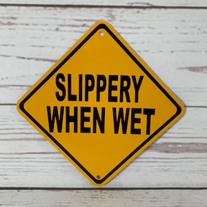 May include: A yellow diamond-shaped warning sign with black text that reads "SLIPPERY WHEN WET".