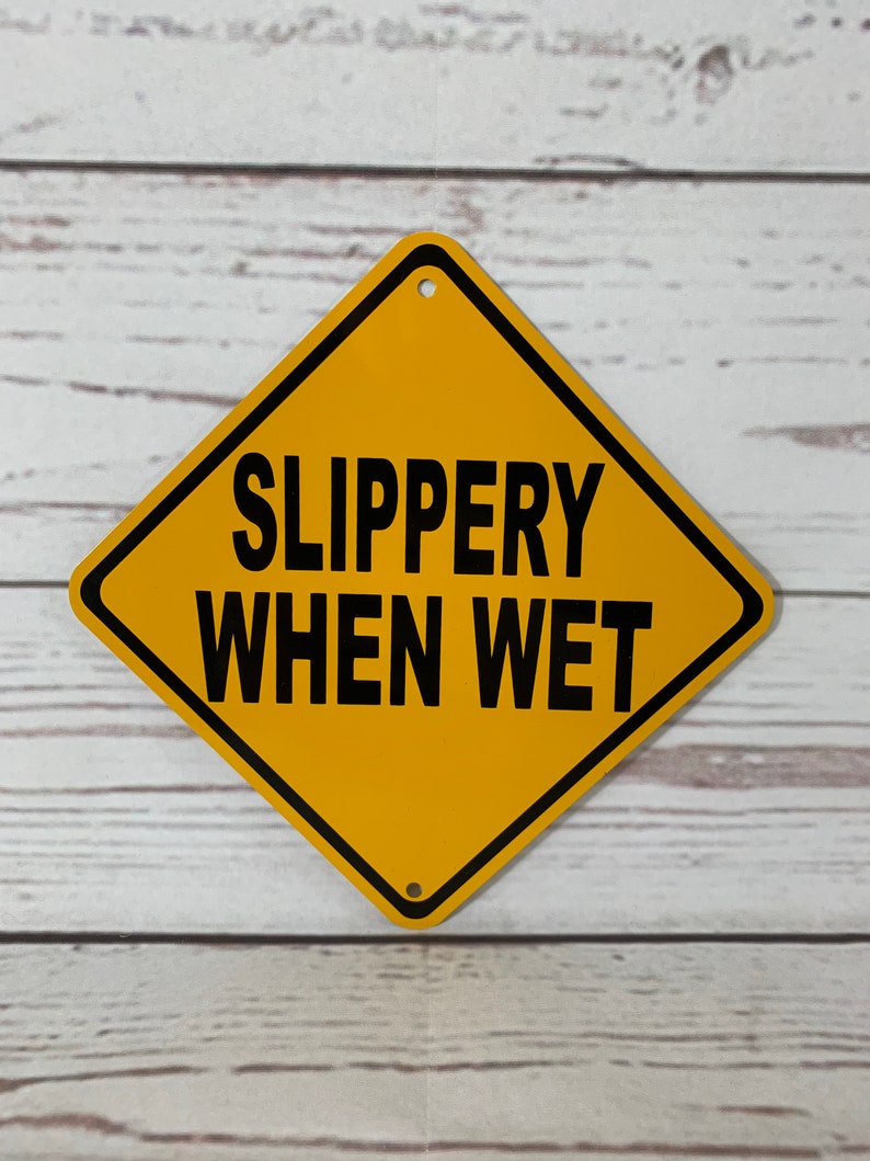 May include: A yellow diamond-shaped warning sign with black text that reads "SLIPPERY WHEN WET".
