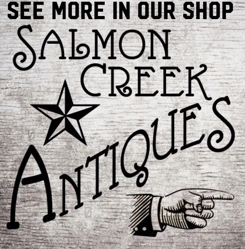 K&ouml;nnte beinhalten: Ein Schild im Vintage-Stil mit dem Text "SEE MORE IN OUR SHOP" oben. Die Worte "SALMON CREEK ANTIQUES" werden in einer dekorativen Schriftart mit einem Stern und einer Hand, die zeigt, angezeigt.