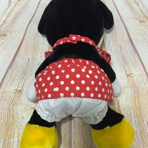 K&ouml;nnte beinhalten: Pl&uuml;schtier einer Zeichentrickfigur, von hinten gesehen. Die Figur hat einen schwarzen Kopf und Ohren, einen roten Polka-Dot-Rock und wei&szlig;e Bloomers mit Spitzenbesatz. Gelbe F&uuml;&szlig;e und eine rote Polka-Dot-Schleife vervollst&auml;ndigen den Look.