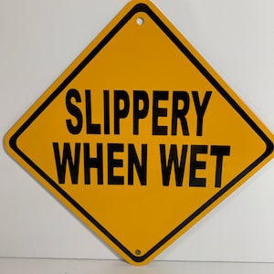 May include: Yellow diamond-shaped warning sign with black border and text that reads "SLIPPERY WHEN WET".