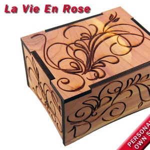 May include: A wooden box with a floral design carved into the top. The box is made of cedar wood and has a dark brown stain. The top of the box is engraved with the words 'La Vie En Rose'. The box is personalized with your own special message.