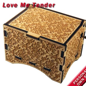 May include: A wooden music box with a floral design and a hand crank. The music box is engraved with the words 'Love Me Tender.' The text 'PERSONALIZE WITH YOUR OWN SPECIAL MESSAGE' is also visible in red.
