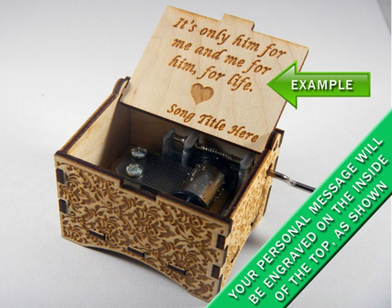 May include: A wooden music box with a floral design on the outside. The lid is open and has a personalized message engraved on the inside: "It's only him for me and me for him, for life." The message is followed by "Song Title Here".