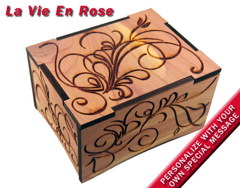 May include: A wooden box with a floral design carved into the top. The box is made of cedar wood and has a dark brown stain. The top of the box is engraved with the words 'La Vie En Rose'. The box is personalized with your own special message.