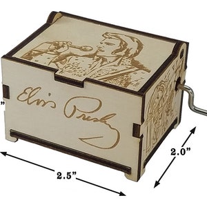K&ouml;nnte beinhalten: Eine Holz-Musikbox mit einem Bild von Elvis Presley auf der Oberseite. Die Musikbox ist 6,35 cm breit, 5,08 cm tief und 4,45 cm hoch. Die Musikbox hat einen Aufziehschl&uuml;ssel an der Seite und spielt Musik, wenn sie aufgezogen wird.