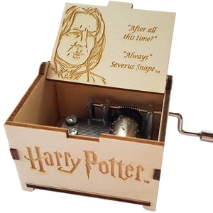 May include: A wooden music box with a hinged lid featuring a portrait of Severus Snape. The lid is open and the inscription reads "After all this time?" "Always" Severus Snape TM. The box is engraved with "Harry Potter TM" on the front.