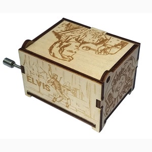 K&ouml;nnte beinhalten: Holzspezielle Musikbox mit einem Laser-gravierten Bild von Elvis Presley auf der Vorder- und der Seite. Die Musikbox hat eine Handkurbel an der Seite.
