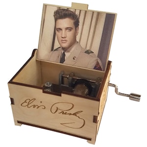 K&ouml;nnte beinhalten: Eine Holz-Musikbox mit einem Bild von Elvis Presley in seiner Milit&auml;runiform auf dem Deckel. Die Musikbox hat eine Handkurbel an der Seite und die Aufschrift "Elvis Presley" auf der Vorderseite.