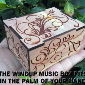 May include: A small wooden music box with a floral design carved into the top. The box is made of cedar wood and has a dark brown stain. The box is small enough to fit in the palm of your hand.