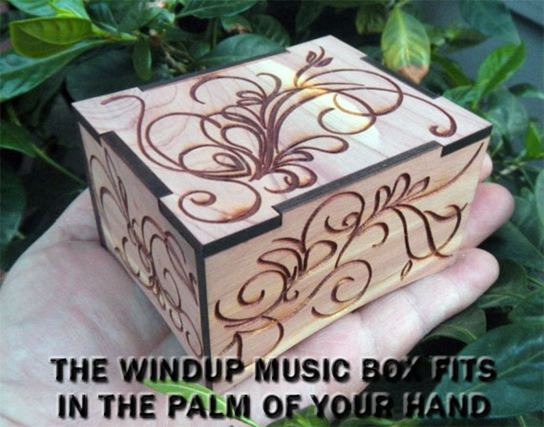 May include: A small wooden music box with a floral design carved into the top. The box is made of cedar wood and has a dark brown stain. The box is small enough to fit in the palm of your hand.